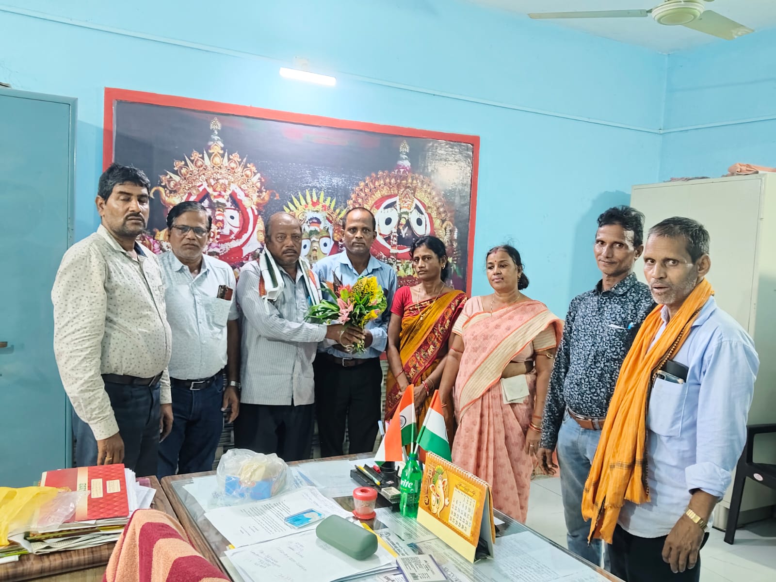 Faculty and staff presenting a bouquet during a felicitation ceremony in the school office